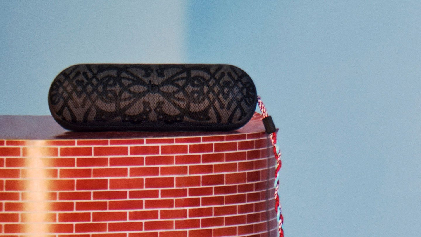Kiko Kostadinov Beats Pill speaker shown with custom grille design in grey and colourful braided lanyard