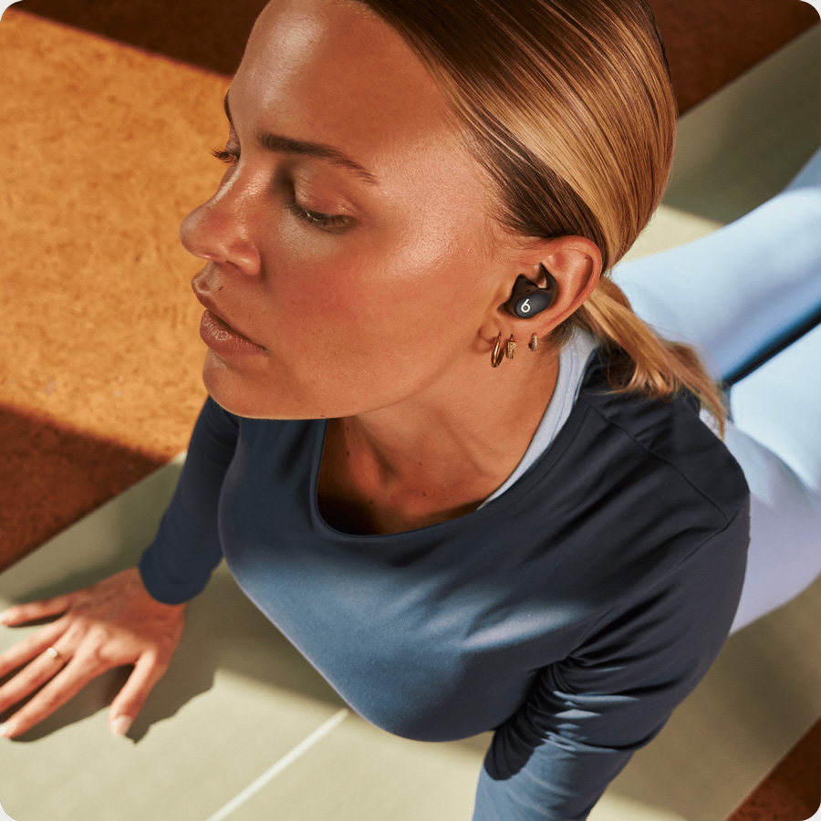 Person wearing Powerbeats Fit earbuds demonstrating their noise control features 