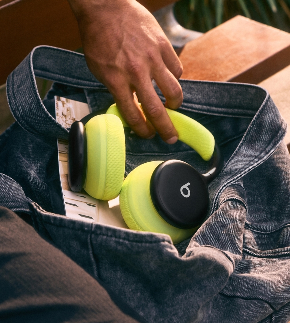 A hand placing Beats 360 headphones with Volt cushions into a denim tote bag