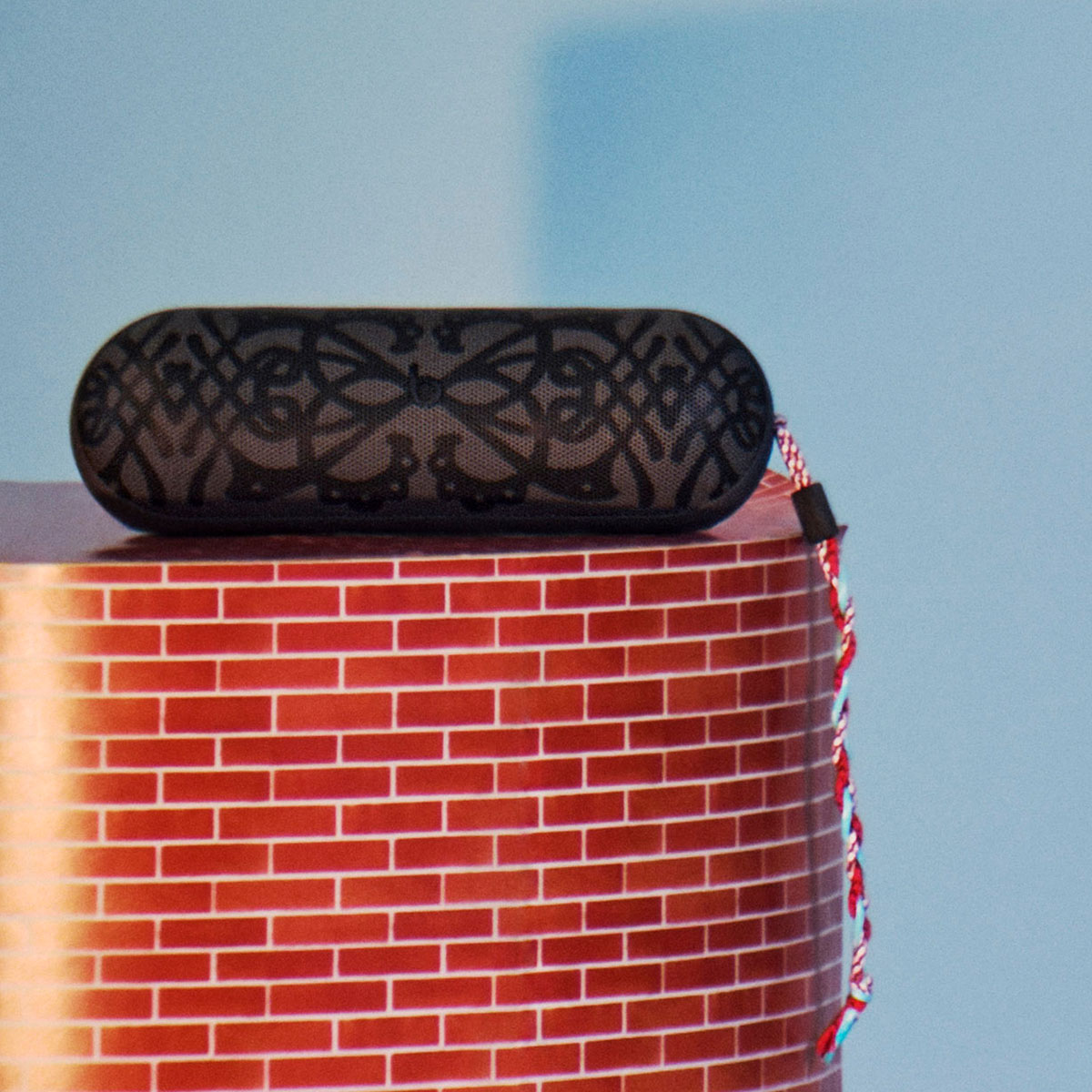 Kiko Kostadinov Beats Pill speaker shown with custom grill design in gray and colorful braided lanyard