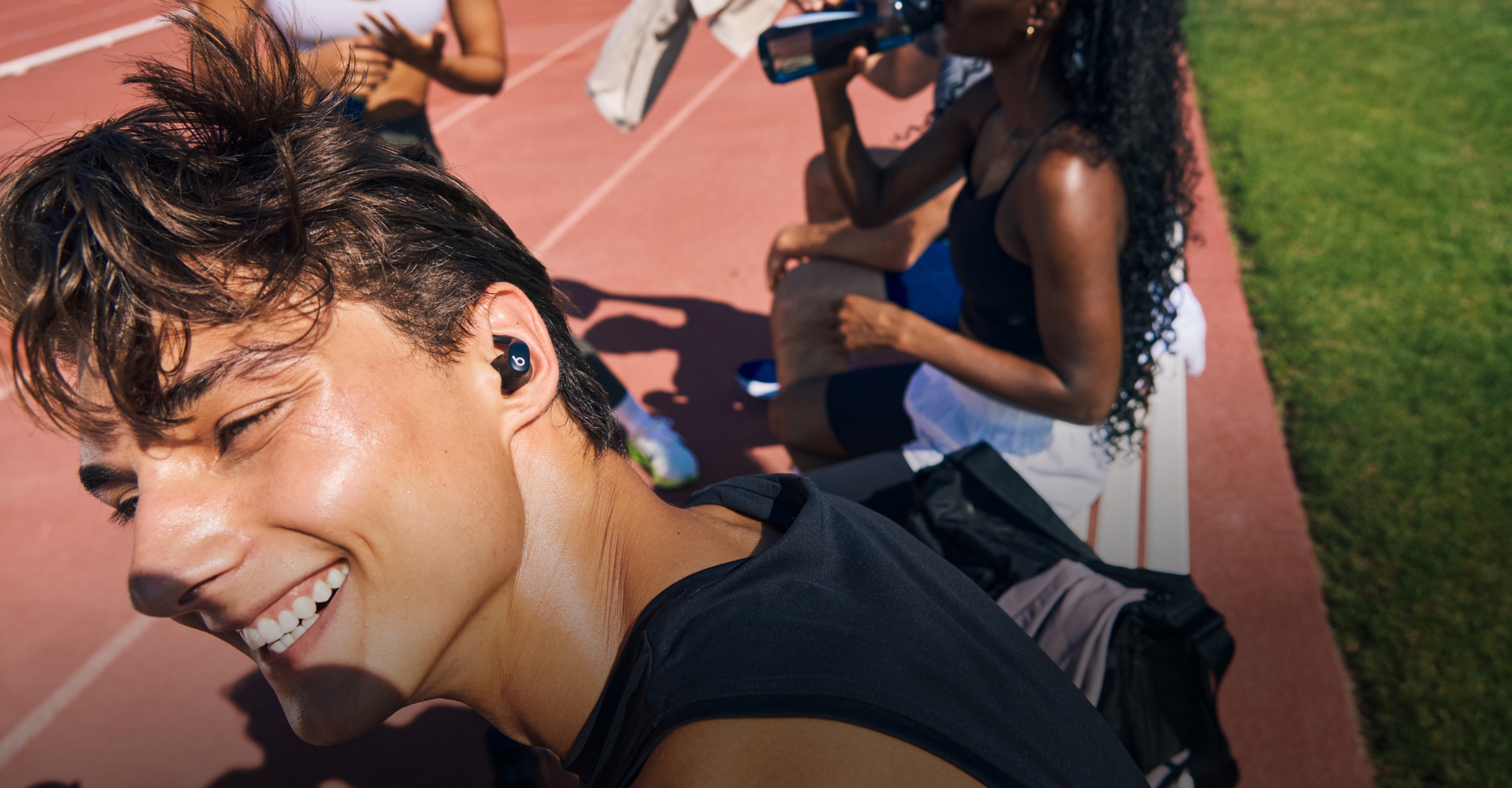 Close-up of an athlete wearing a black Powerbeats Fit earbud during an outdoor track workout.