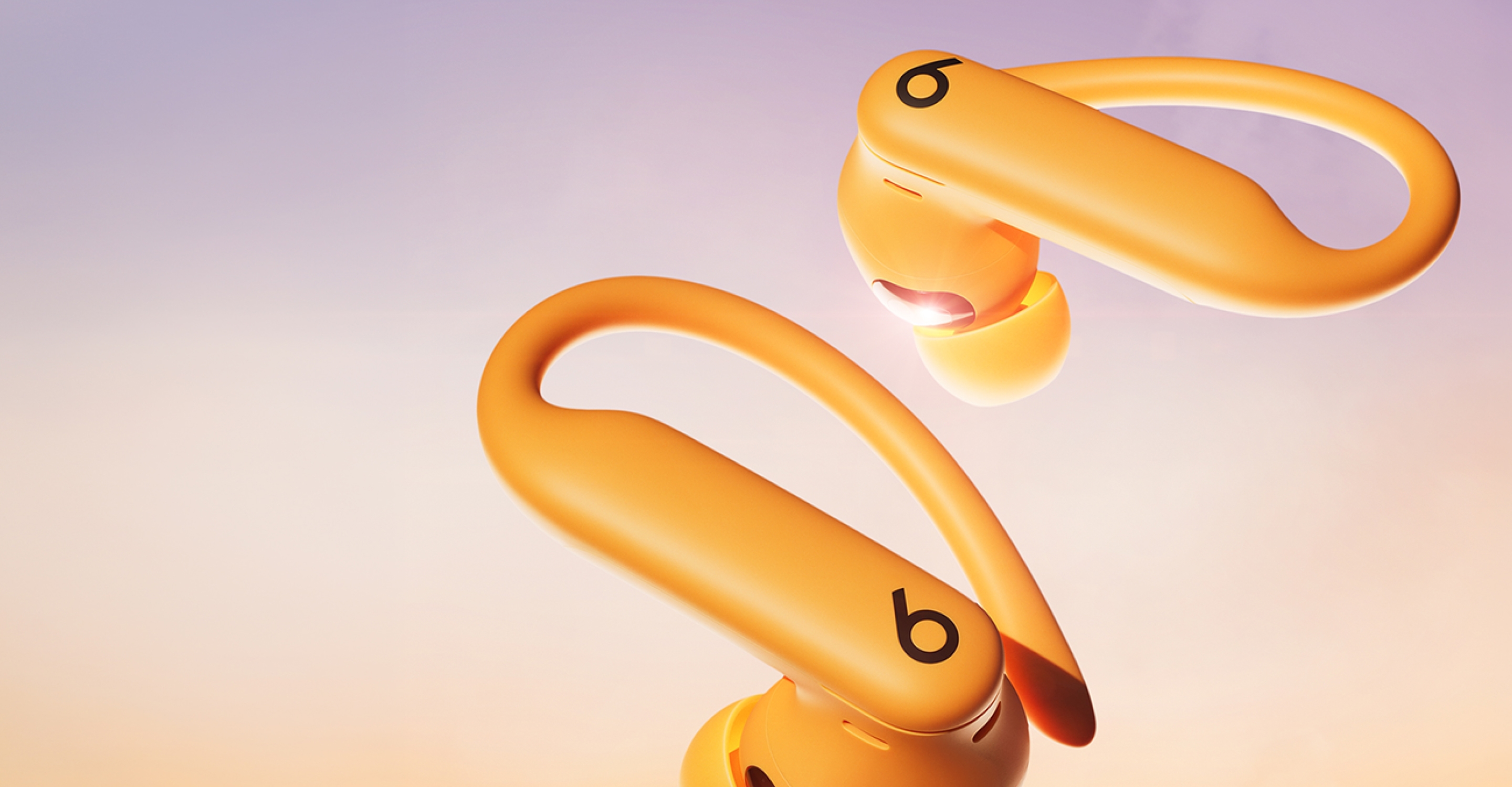 Close-up of electric orange Powerbeats Pro wireless earbuds highlighting the secure-fit ear hooks.