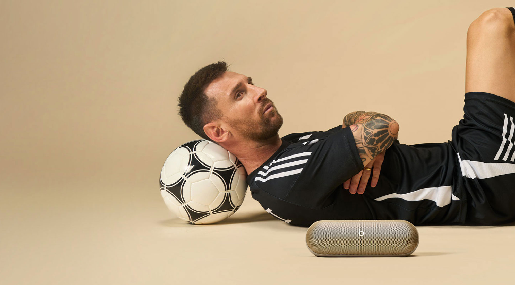 Lionel Messi lying down with his head on a soccer ball, next to the Beats Pill