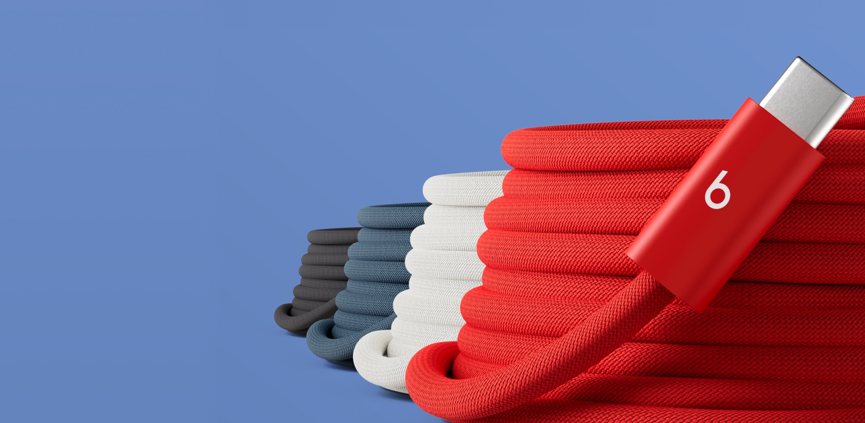 Coiled Beats 3-metre USB-C charging cables in four colours – Rapid Red, Surge Stone, Nitro Navy and Bolt Black – stacked together against a blue background.
