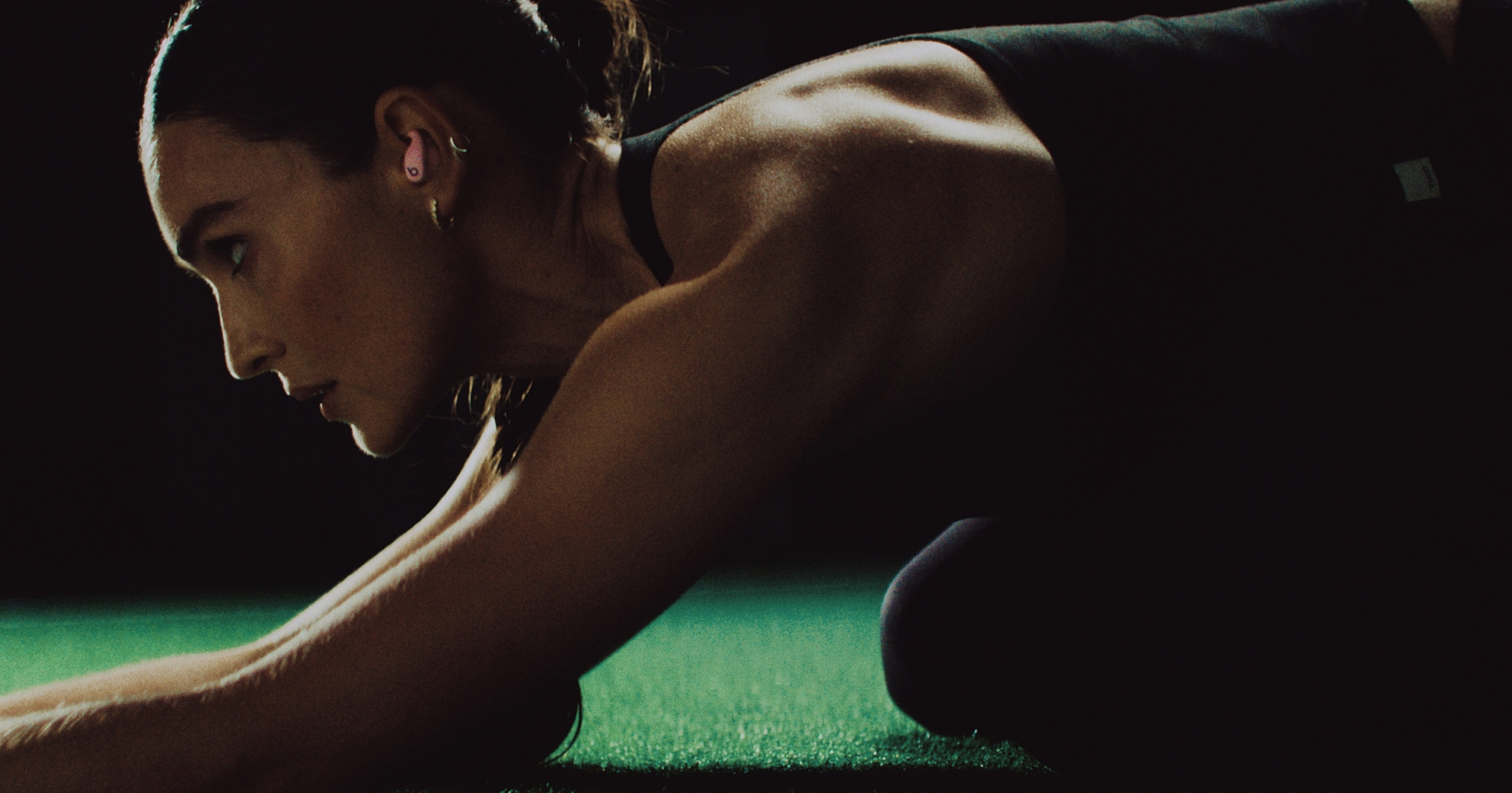 Kirsty Godso working out while wearing pink Powerbeats Fit earbuds.