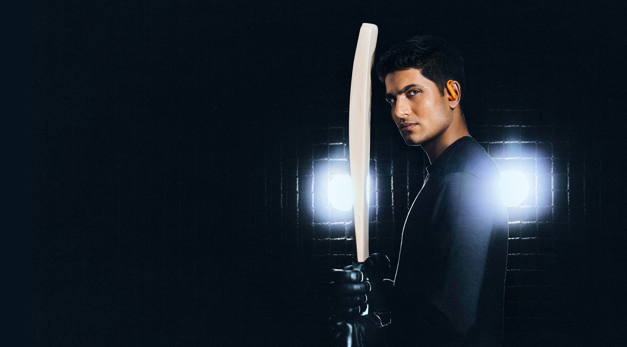 Shubman Gill wearing Powerbeats Pro 2 earbuds and holding a cricket bat.