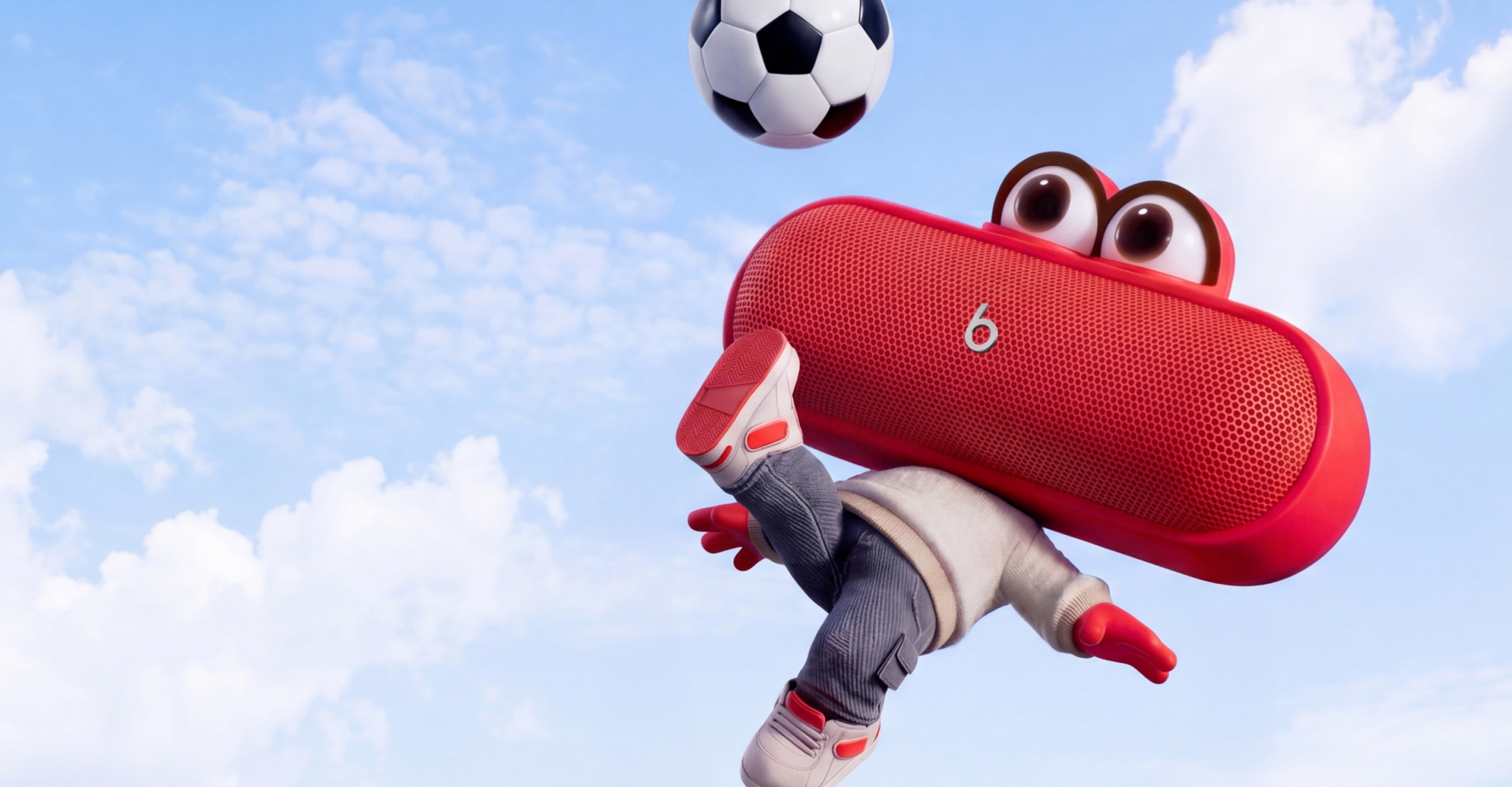 Um personagem animado da caixa de som Beats Pill People, com olhos e pernas de desenho animado, executando um chute de bicicleta com uma bola de futebol contra um céu azul brilhante, com o texto "Bora chutar?".