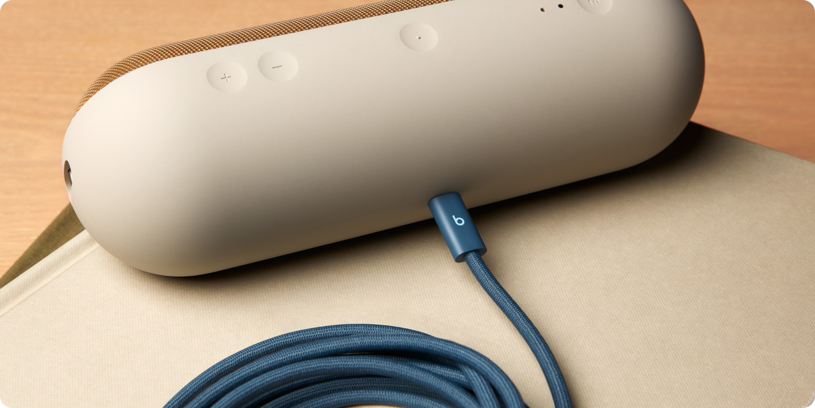 A coiled Beats 240W USB-C to USB-C Cable plugged into electronic devices to demonstrate fast charging.