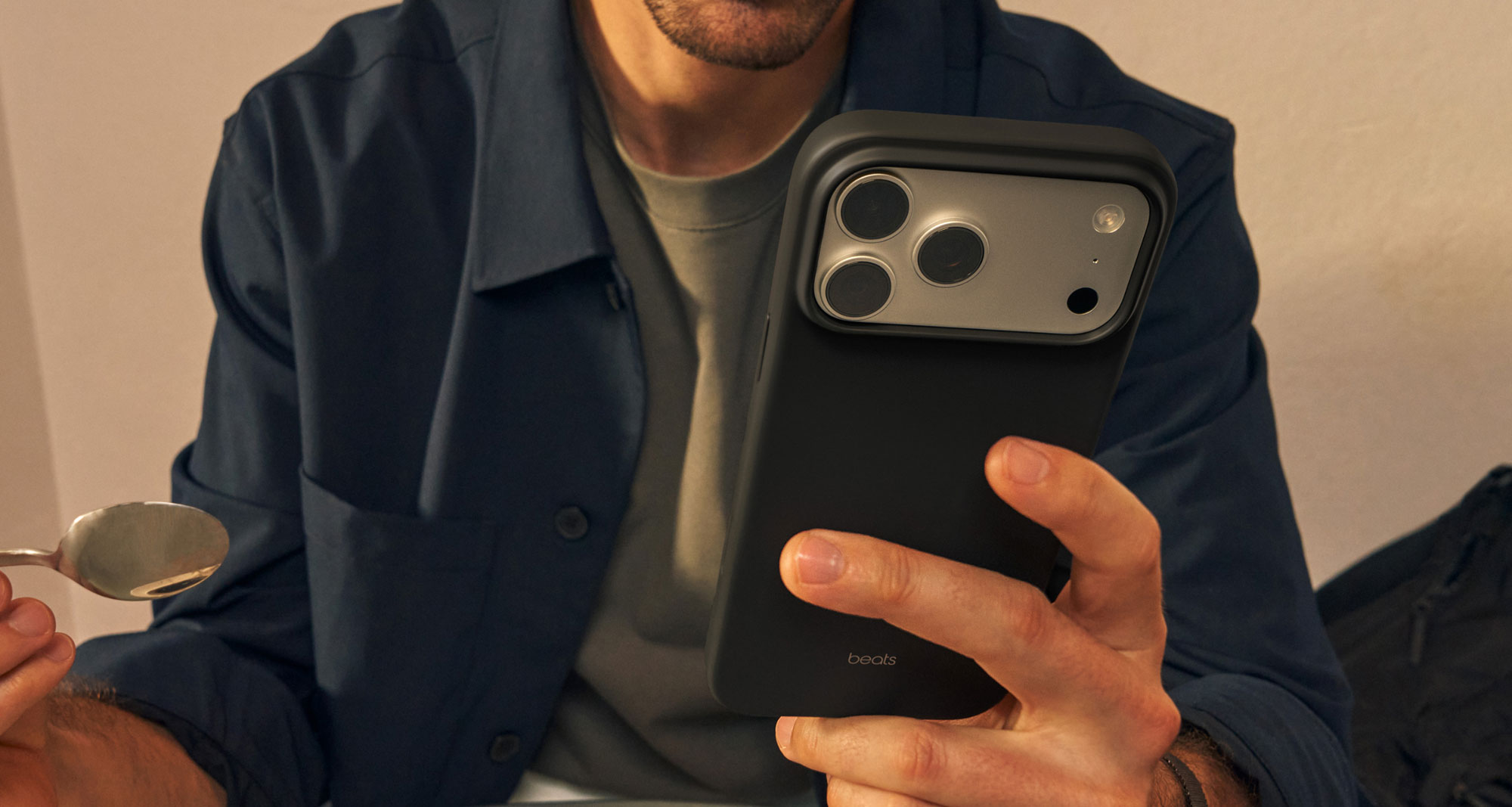 A person holding the Beats iPhone 17 Case with MagSafe and Camera Control in Granite Gray featuring an outer matte finish which helps reduce smudges and scratches.