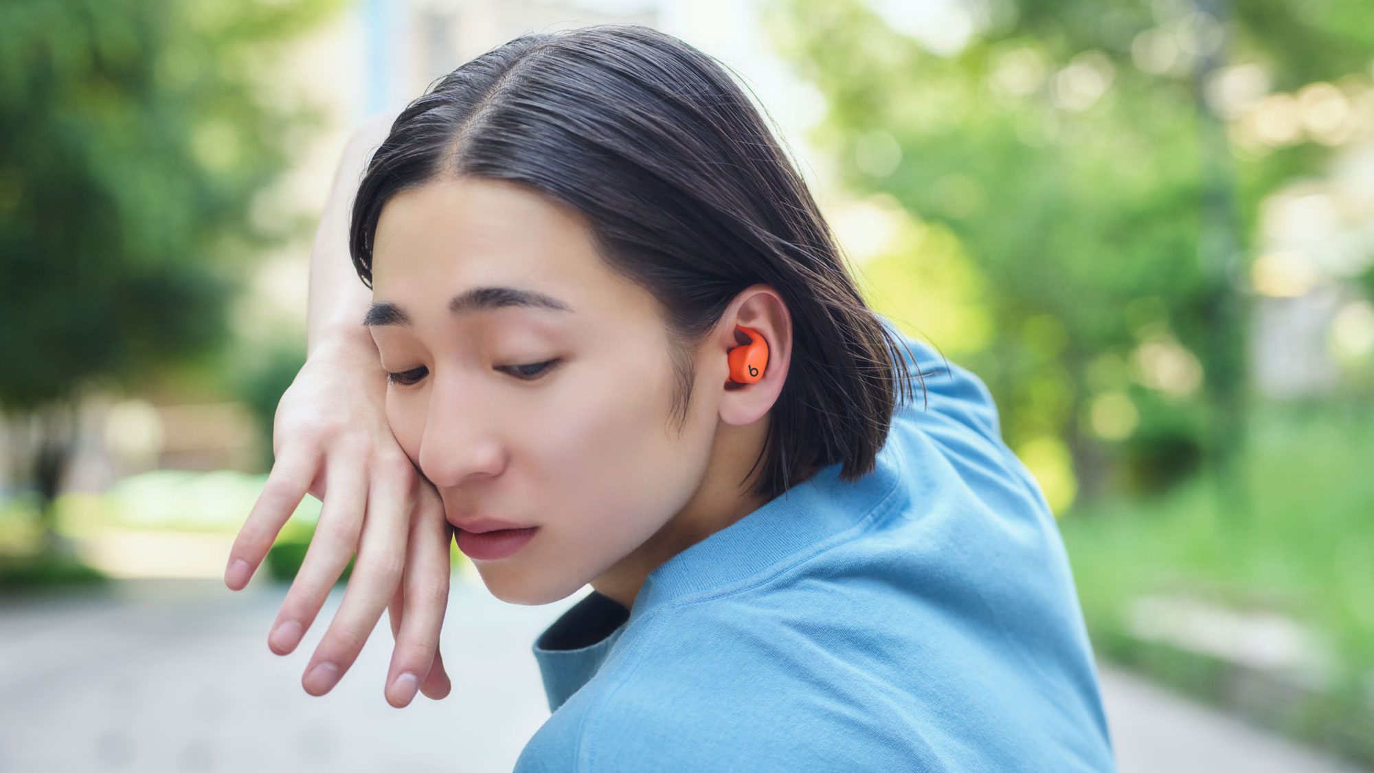Powerbeats Fitのスパークオレンジを装着している人物