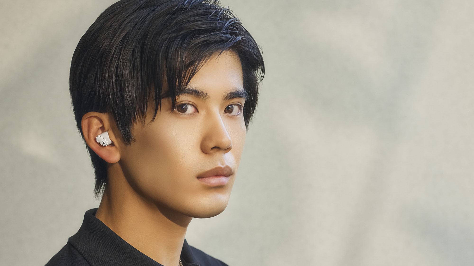 アイボリー色のBeats Studio Buds +を装着している人物。