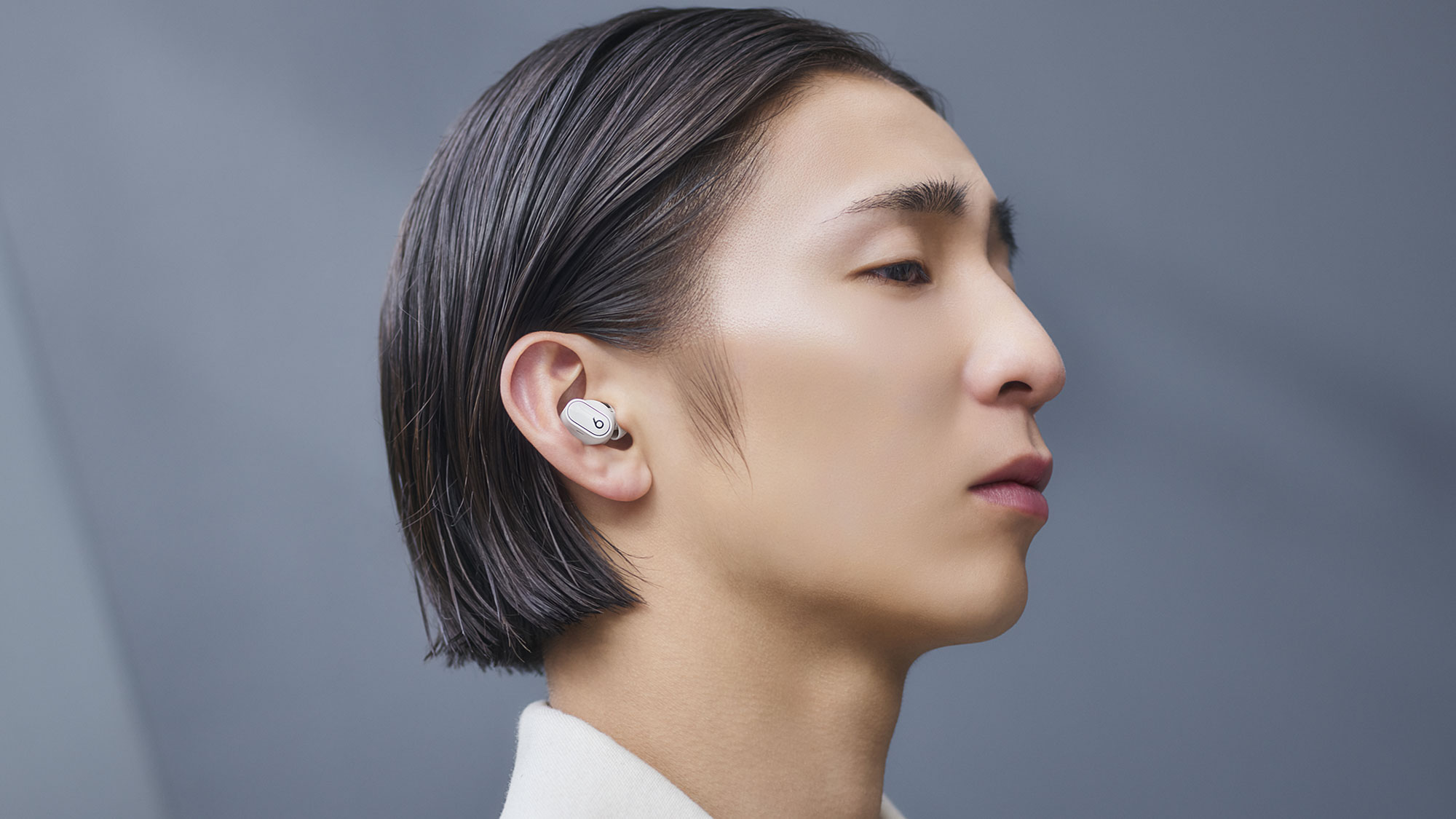 アイボリー色のBeats Studio Buds +を装着している人物。