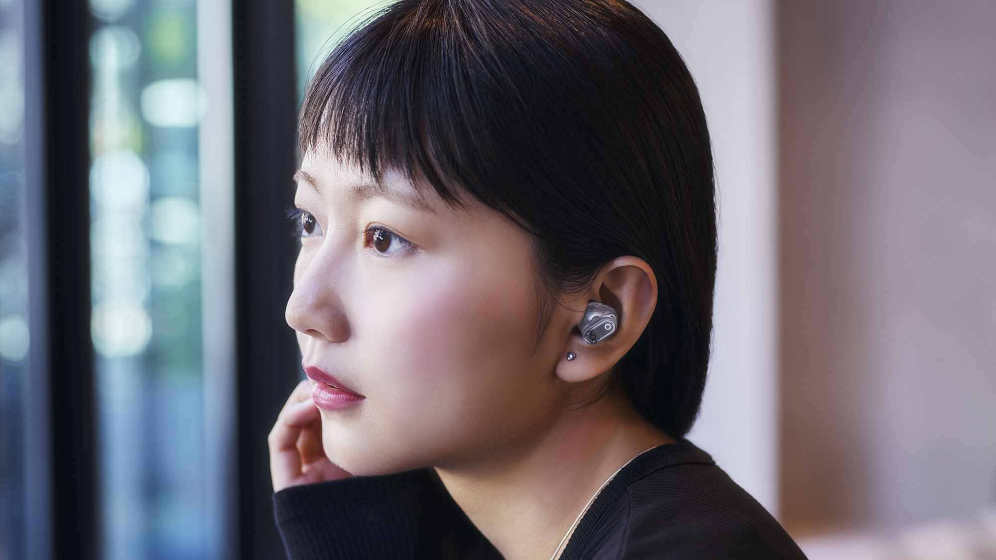 トランスペアレントのBeats Studio Buds +を装着している人物