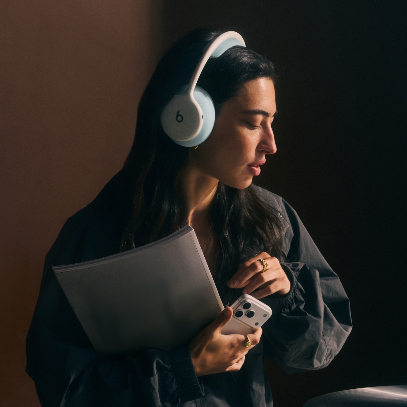 Person wearing Beats 360 headphones and holding an iPhone to demonstrate exceptional call quality and Active Noise Cancelling
