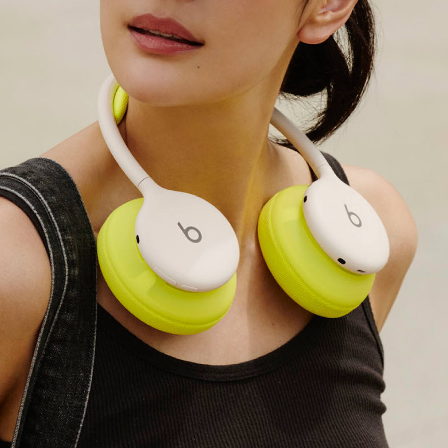 スカイのPerformance Knitヘッドセットクッションとイヤーカップクッションを付けたクラウドのBeats 360を、折りたたんだ状態で首にかけている人物
