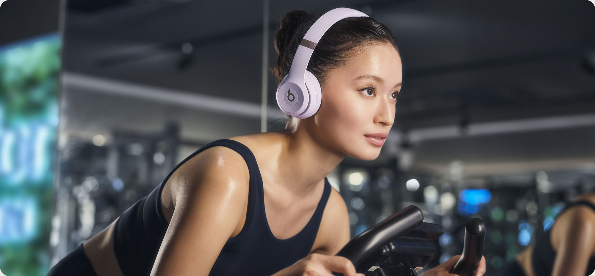 Beats Solo 4ヘッドフォンを装着してエアロバイクに乗っている女性